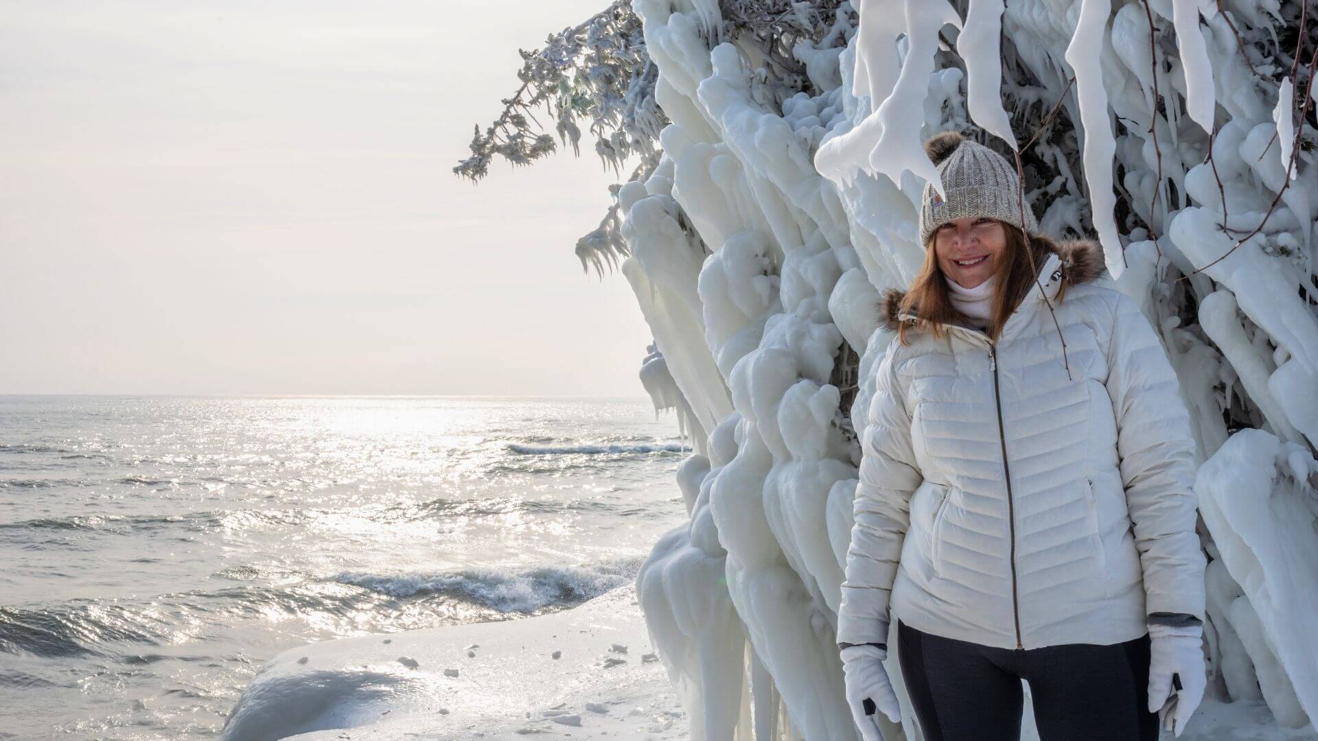 tourist posing next to icy shoreline in door county wisconsin